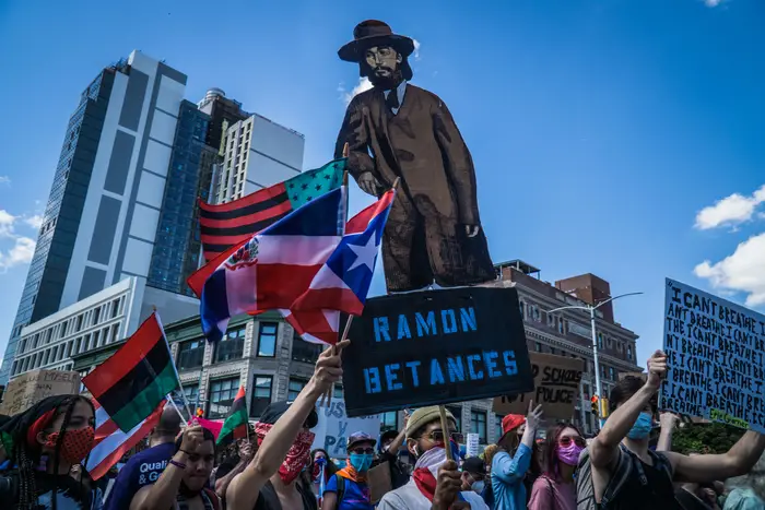 An illustration of Puerto Rican independence figure Ramón Emeterio Betances is held up by marchers on June 14, 2020